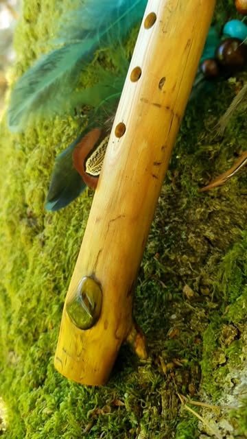 Close-up of a golden branch flute on moss with feathers