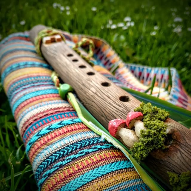A flute decorated with moss and toadstools on a woven blanket
